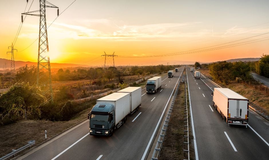 Several trucks travel on a divided highway.