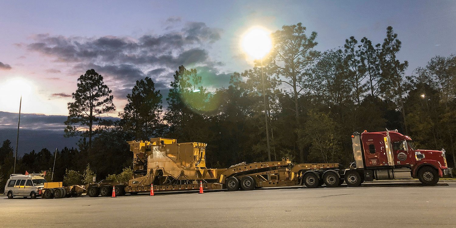 11-axle heavy haul truck parked in lot near pilot car