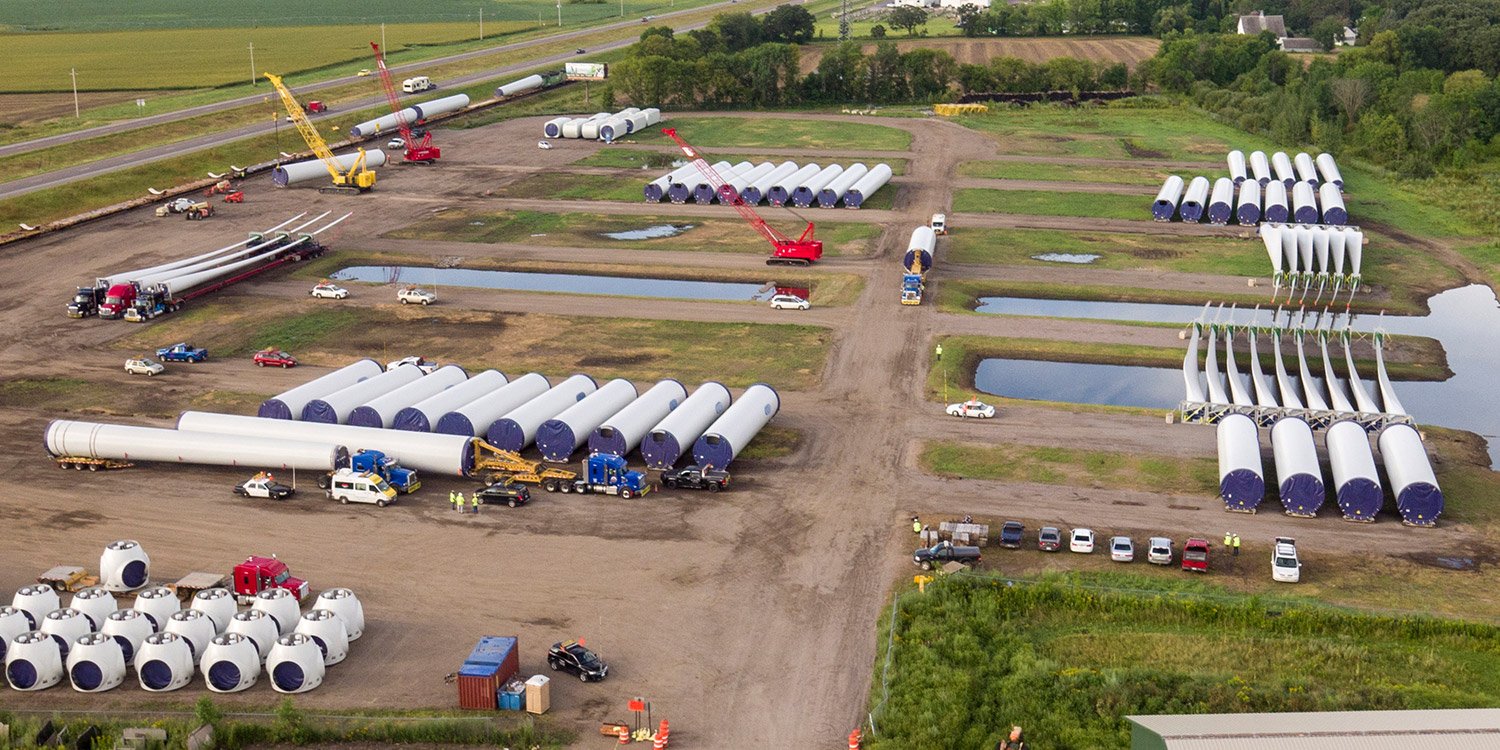 Cranes and semi trucks working on wind component site