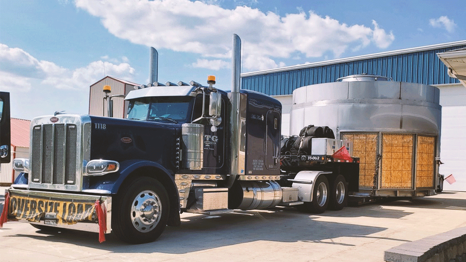 A black ATS truck hauling an oversized load