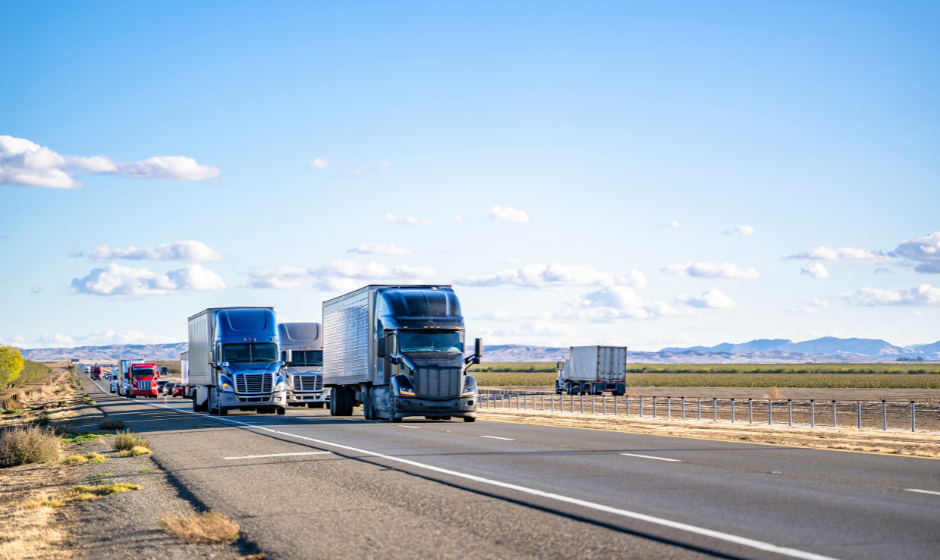 Several trucks travel on a divided highway.