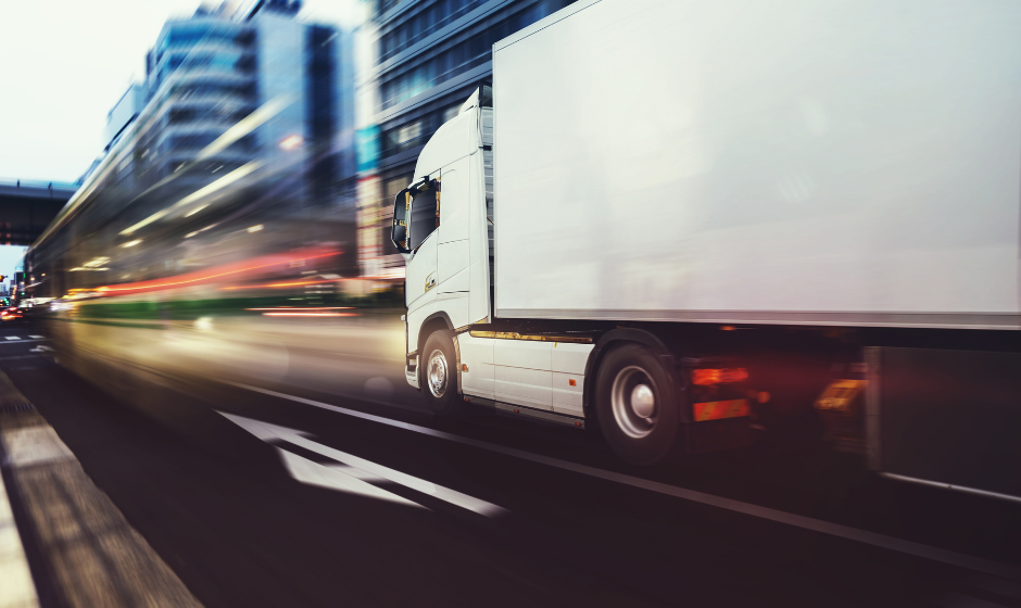 A dry van truck traveling quickly in a metropolitan area