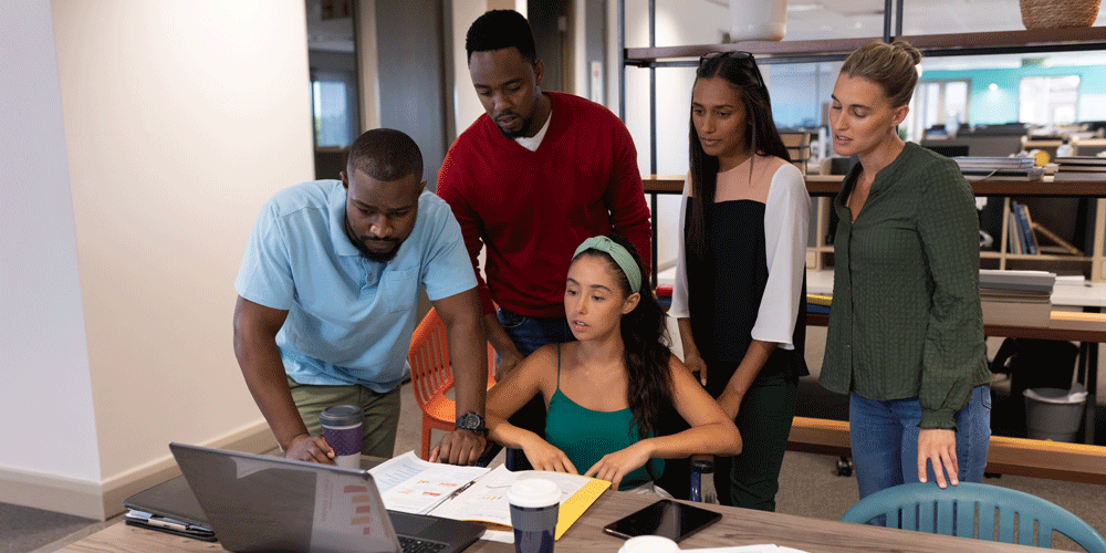 Multiracial male and female advisors looking over a laptop screen.