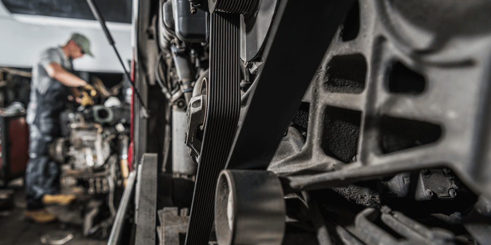 Close up view of an engine with a diesel mechanic in the background.