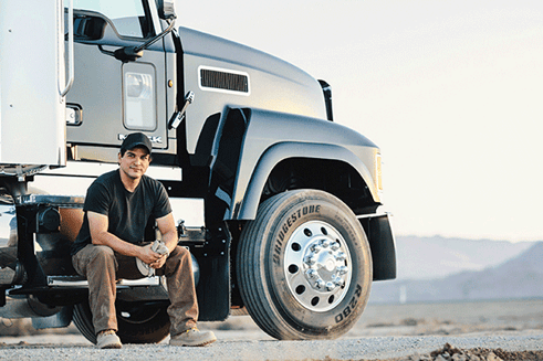 Truck Driver sitting on the cab steps of his semi truck