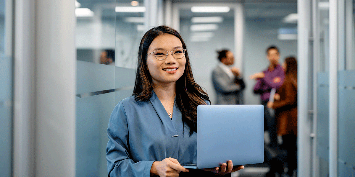 Young Asian woman smiling as she holds her laptop.