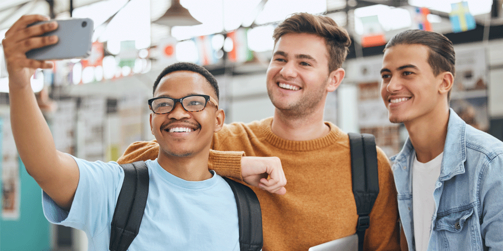 Group of three college-aged men smiling for a selfie.