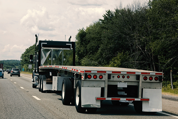 A flatbed truck travels on a highway